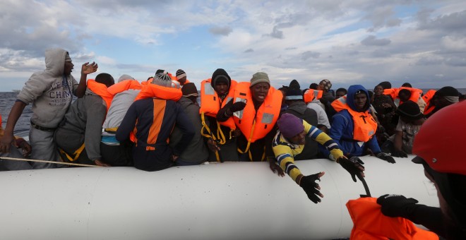 Un voluntario de Proactiva Open Arms acerca un achaleco salvavidas a los inmigrantes que tratan de rescatar en el Mediterráneo.-REUTERS/Yannis Behrakis