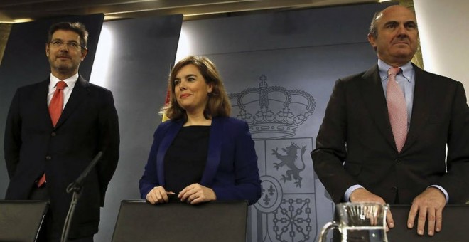 La vicepresidenta del Gobierno, Soraya Sáenz de Santamaría, flanqueada por el ministro de Justicia, Rafael Catalá (izda.), y el ministro de Economía, Luis de Guindos. EFE