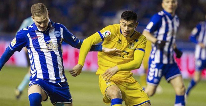 El defensa del Alcorcón Fede Vega (c) lucha por el balón con el delantero del Deportivo Álaves Christian Santos (i). | ADRIÁN RUIZ DEL HIERRO (EFE)