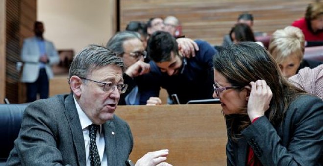 El presidente de la Generalitat valenciana, Ximo Puig, conversa con la vicepresidenta del Consell, Mónica Oltra, al comienzo del pleno que, entre otros puntos, debate y vota el proyecto de ley de la función social de la vivienda. EFE/Manuel Bruque