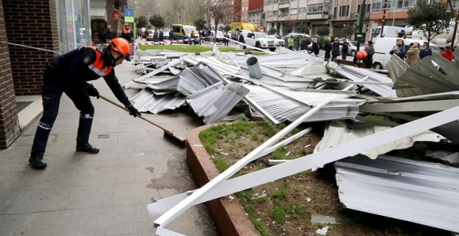 Efectivos de Protección Civil se disponen a apartar las piezas del tejado de un edificio de Vigo. / SALVADOR SAS (EFE)