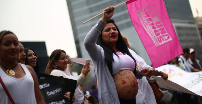 A pregnant woman holds a flag as she takes part in a march on International Women's Day in Mexico City, Mexico, March 8, 2017. The flag reads, 'Not one (woman) less. Alive we want us'. REUTERS/Edgard Garrido