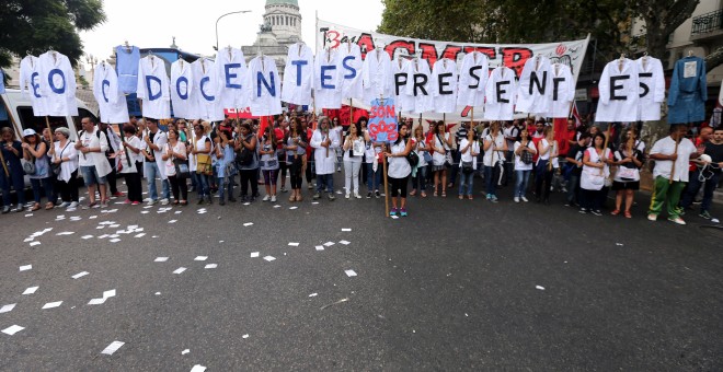 Maestros de escuelas públicas en huelga sostienen uniformes que forman las palabras 'Maestros presentes' fuera del Congreso durante una protesta en Buenos Aires, Argentina. REUTERS / Marcos Brindicci