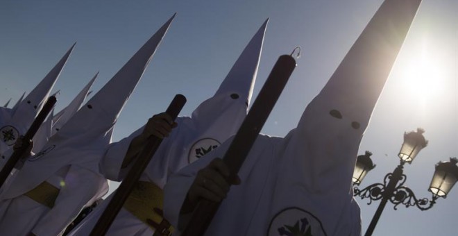 Nazarenos de la cofradía de San Gonzalo en el puente de Triana en esta calurosa tarde del lunes santo. EFE/Raúl Caro