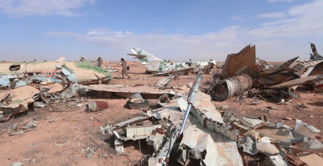 Un miliciano de las Fuerzas de Siria Democrática pasa junto a los restos de aviones destruidos ne la ciudad de Raqqa. - REUTERS