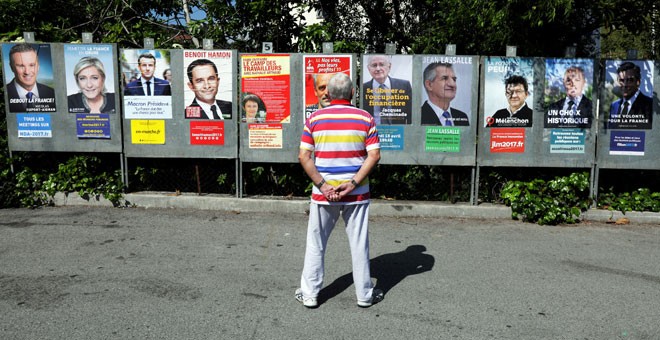 Un hombre mira los carteles de la campaña de los hasta 11 candidatos que se presentan a las elecciones presidenciales francesas. REUTERS/Eric Gaillard