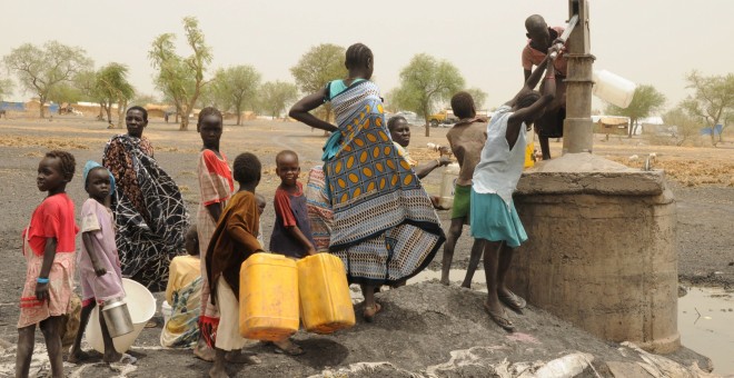 Mujeres y niños recogen agua de un pozo en un campamento de Sudán del Sur.REUTERS / Jok Solomun