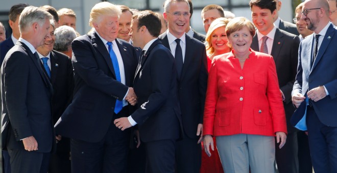 El Presidente estadounidense Donald Trump y su homólogo francés Emmanuel Macron se saludan con un apretón de manos frente a otros líderes mundiales en la Cumbre de la OTAN REUTERS/Jonathan Ernst