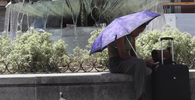 Una mujer se protege del sol con un paraguas en la madrileña Puerta del Sol coincidiendo con el inicio de la primera 'ola de calor' del año. EFE/Ballesteros