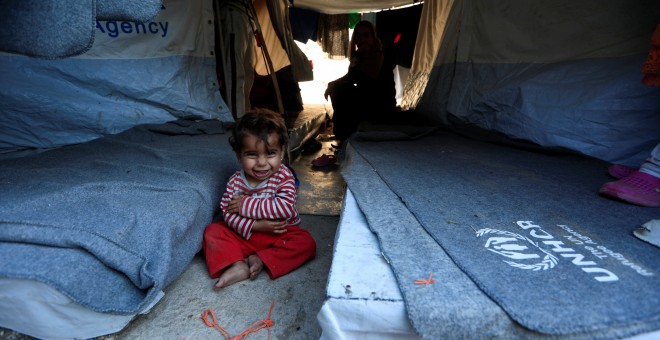 Una niña de un año sonríe sentanda con su madre en el campo de refugiados de Souda, en Grecia. 'Estoy devastada porque en estos momentos no puedo solicitar reunificación familiar porque tengo que esperar a que mi esposo reciba los papeles de asilo. Me sie