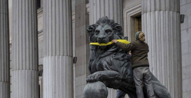 Una activista de Greenpeace amordaza los leones del Congreso de los Diputados. - Foto: EFE