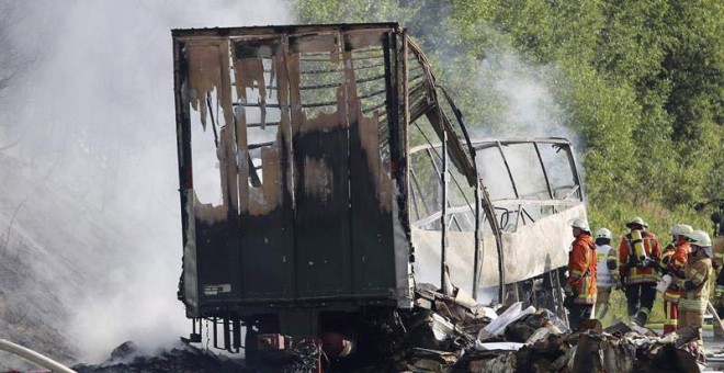 Los bomberos trabajan junto a los restos calcinados de un autobús en la carretera A9 en la zona de Núremberg cercana a Münchberg (Alemania). | STEPHAN FRICKE (EFE)