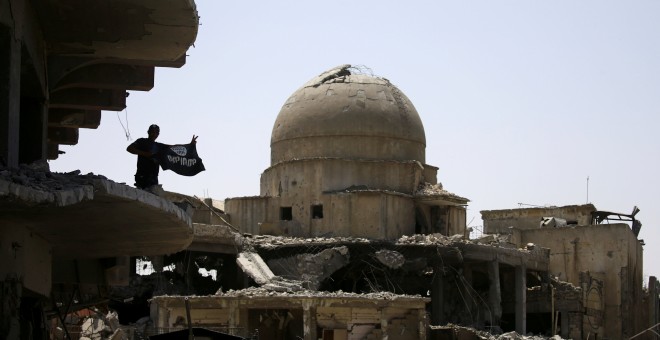 Un miembro de las fuerzas iraquíes levanta una bandera del Estado Islámico sobre un edificio destruido en la batalla en Mosul REUTERS/Thaier Al-Sudani