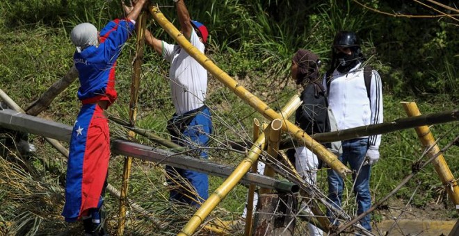 Opositores venezolanos preparan una barricada.EFE/Miguel Gutiérrez