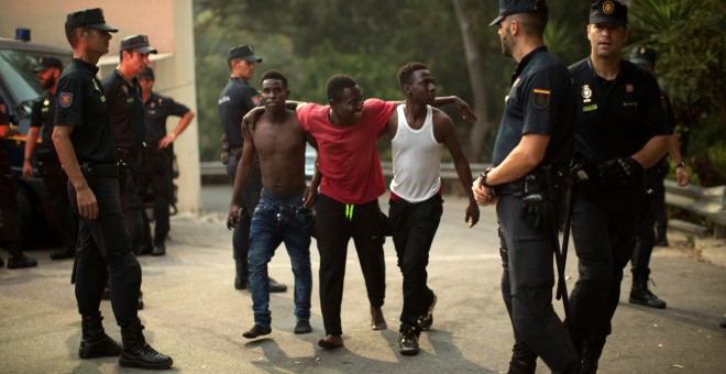 Agentes de la Guardia Civil junto a tres de los migrantes tras cruzar la frontera. REUTERS