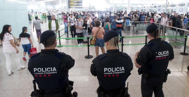 Agentes de los Mossos d'Esquadra controlan de los accesos a las puertas de embarque en el Aeropuerto de El Prat. .- Quique García (EFE)