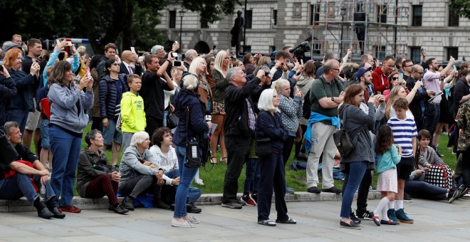 Las personas concentradas junto al 'Big Ben' toman imágenes con sus smartphone de las campanadas del reloj, antes de su parada por las obras de restauración. REUTERS/Peter Nicholls