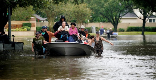 Varios vecinos de Houston usan un bote para salir de sus casas. - REUTERS