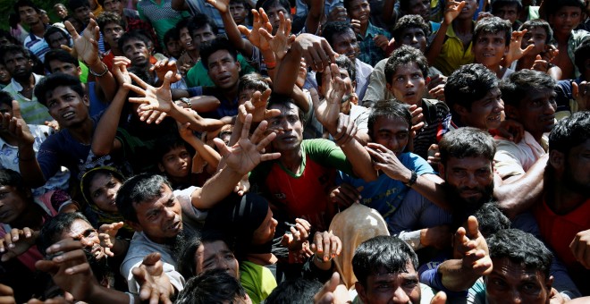 Los refugiados rohinya extienden su mano para alcanzar los suministros de socorro que les proporcionan las autoridades locales de Bangladesh, en el campamento improvisado de Cox. REUTERS / Mohammad Ponir Hossain