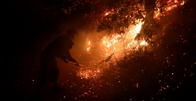 Un vecino intenta apagar las llamas cerca de Vigo.- REUTERS