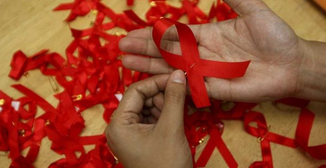 Una joven prepara lazos rojos durante una campaña de concienciación sobre la prevención del contagio del sida. - EFE