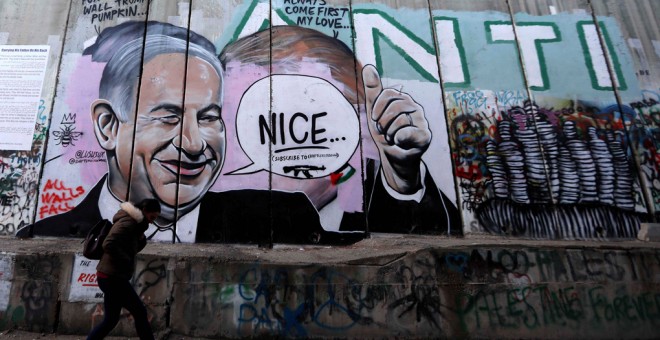 Una mujer camina junto a un graffiti del primer ministro, Benjamín Netanyahu, en el muro de separación israelí de la ciudad cisjordana de Belén. EFE/Abed Al Hashlamoun