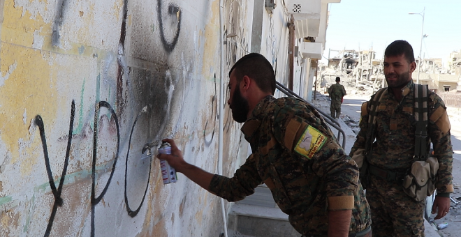 Combatientes de la milicia kurda YPG realizan una pintada en las calles de Raqqa./ FERRAN BARBER