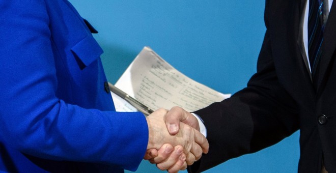 La canciller alemana y líder de la Unión Cristianodemócrata (CDU), Angela Merkel, y el líder del Partido Socialdemócrata (SPD), Martin Schulz, se saludan después de una rueda de prensa tras las negociaciones para formación de Gobierno, en Berlín (Alemania