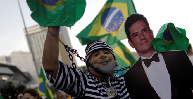 Un hombre disfrazado de preso y una careta de Lula posa con una imagen del polémico juez Sérgio Moro, visto como un héroe entre los antipetistas. - REUTERS