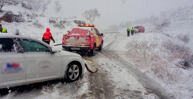 Los bomberos trasladan a un coche durante una nevada. EFE