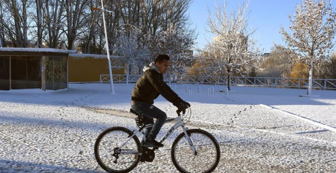 Un hombre se desplaza en bicicleta en medio del temporal de frío y nieve que afecta a León. / EFE