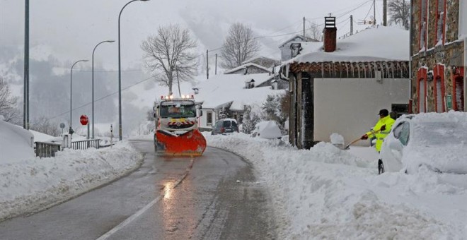 Un vecino del pueblo de Pajares (Asturias) trata de abrir con una pala el camino para sacar su vehiculo ante una camion que limpia la carretera. /EFE