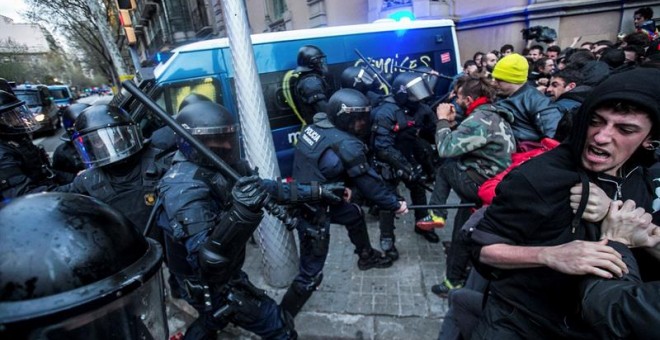 Miembros de los Mossos d´Esquadra impiden el paso de manifestantes en las inmediaciones de la Delegación del Gobierno en Cataluña, donde centenares de independentistas tratan de desbordar el cordón policial en protesta por la detención del expresidente ca