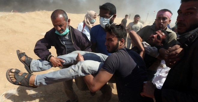 Varias personas trasladan un hombre herido durante las protestas del lunes en Gaza. - REUTERS