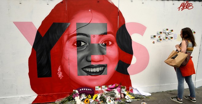 Una mujer observa un mural de Savita Halappanavar con ofrendas de flores en Dublín el día del referéndum en Irlanda sobre la liberalización del aborto. REUTERS/Clodagh Kilcoyne