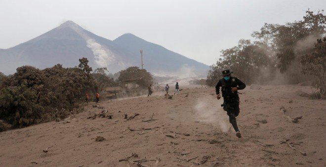Un policía corre por un deslizamiento de fluido del volcán de Fuego en Guatemala. / Reuters
