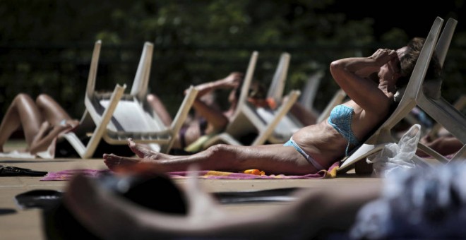 Varios bañistas toman el sol en la piscina municipal al aire libre del Canal de Isabel II/ EFE