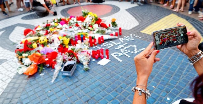 Una turista fotografía los ramos de flores y objetos de todo tipo depositados en el mural de Miro de La Rambla de Barcelona en recuerdo de los atentados en La Rambla y Cambrils. - EFE/Alejandro García