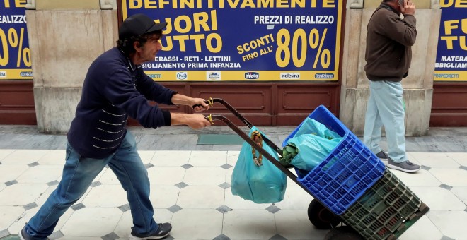 Una persona camina frente a un local con un cartel que dice 'cierre definitivo', en Turín. REUTERS / Stefano Rellandini