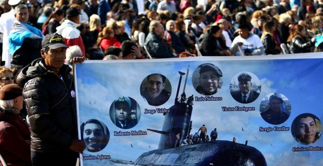 Un hombre sostiene una pancarta con imágenes de algunos tripulantes del submarino argentino ARA San Juan hoy, jueves 15 de noviembre de 2018, durante homenaje al cumplirse un año de su desaparición, en Mar del Plata (Argentina). Los familiares de los 44