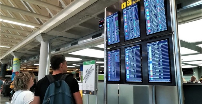 Unos viajeros consultan los paneles de información sobre salidas de vuelos en el aeropuerto de Palma de Mallorca. E.P.
