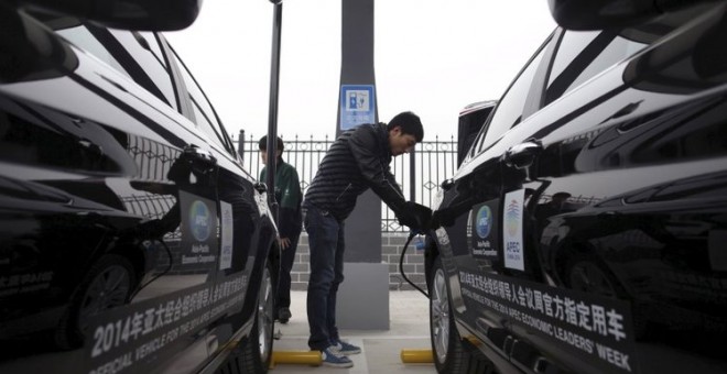 Un hombre carga las baterías de los autos eléctricos en Pekín. REUTERS
