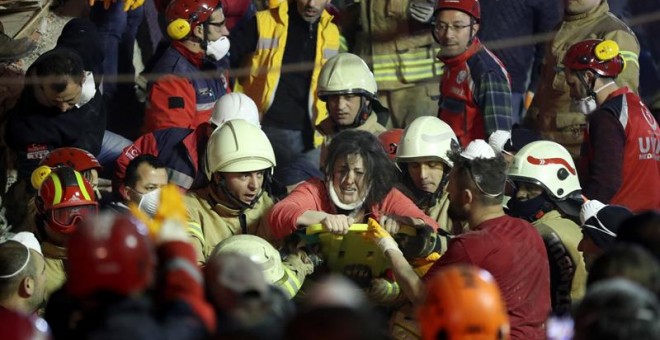 Varios efectivos de los equipos de rescate transportan a una mujer herida, este miércoles en Estambul tras el derrumbe de una edificio de viviendas.-EFE