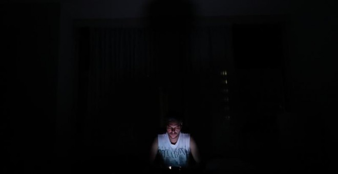 Un hombre mira el movil en la oscuridad este jueves en Caracas (Venezuela), durante un apagón eléctrico que afectó a gran parte del país. Venezuela sufre un nuevo apagón de energía que afecta al menos 11 estados, así como al territorio político administra