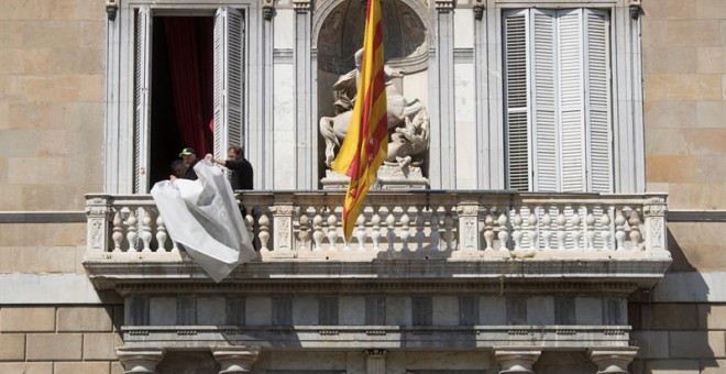 Operarios, terminando de retirar el cartel que colgaba de la fachada del Palau de la Generalitat. - EFE