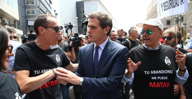 El líder de Ciudadanos, Albert Rivera (c), pasa junto a unos funcionarios de prisiones que se han manifestado este martes en las inmediaciones del Congreso de los Diputados. - EFE