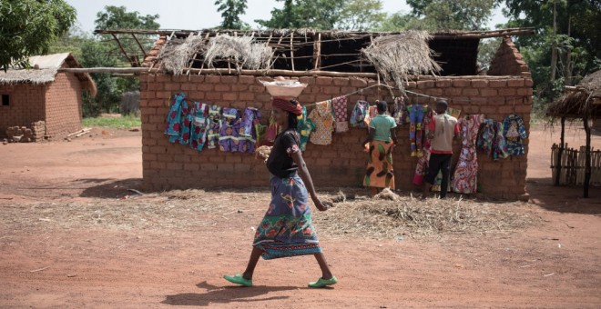 Una mujer pasa junto a unos vendedores de ropa en el pueblo de Awatche. - AFP