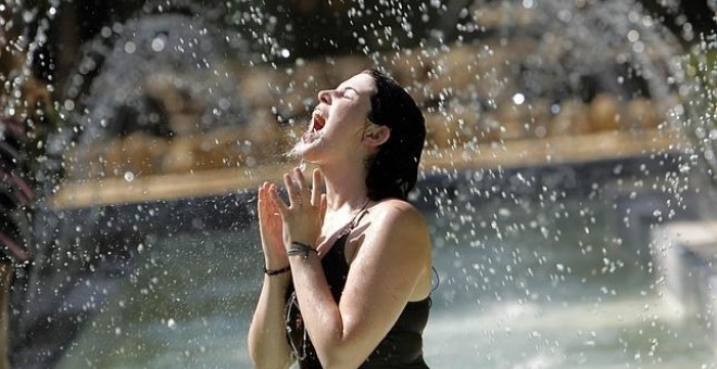 Una joven bebe de una fuente en plena ola de calor. EFE/Archivo