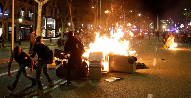 Contenedores ardiendo entre varios manifestantes y los Mossos durante las protestas en el centro de Barcelona. /REUTERS