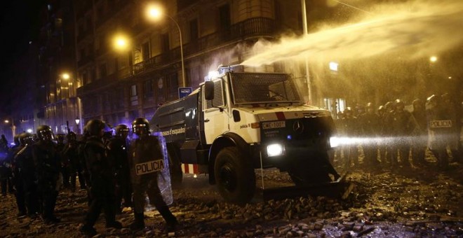 Un grupo de policías antidisturbios junto a la tanqueta de agua a presión durante los altercados que se están produciendo en Barcelona este viernes. /EFE